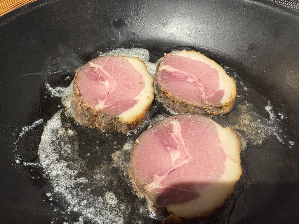 鉄フライパンで焼いている自家製イノシシハムのスライス3枚